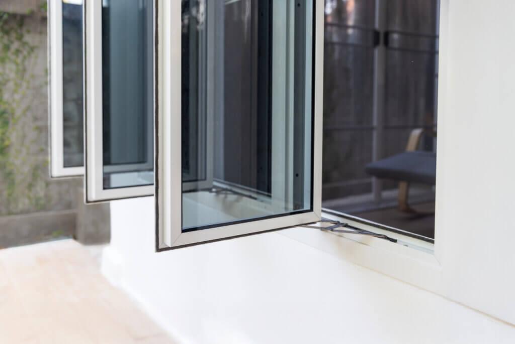 Open casement windows on a white wall, allowing natural cross-ventilation.