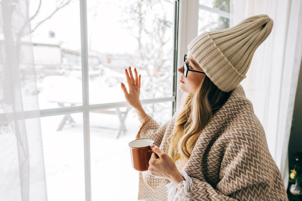 Woman sipping tea in front of window during winter.